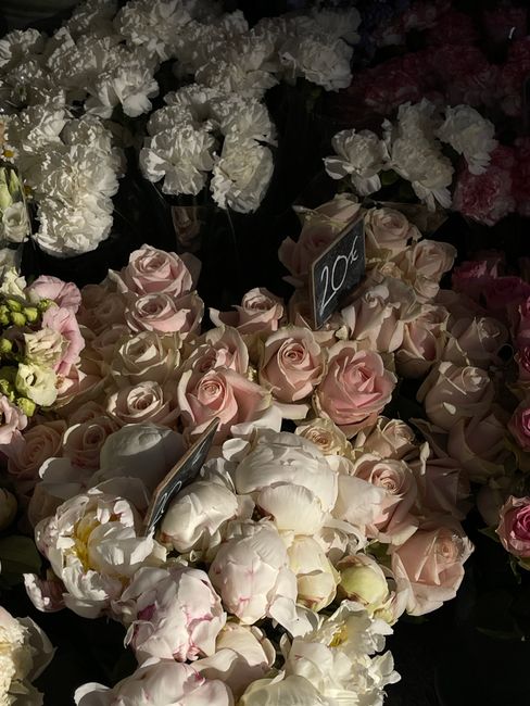 A floral display featuring a variety of soft pink and white roses with delicate, layered petals arranged in a bouquet, resting on a display table among other floral arrangements at Manor House Florist